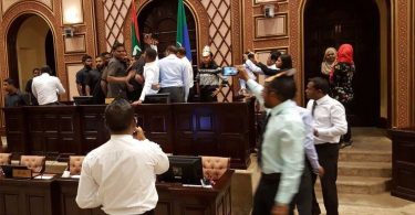 Security forces remove opposition lawmakers gathered at the parliament speaker's table while lawmaker protest.