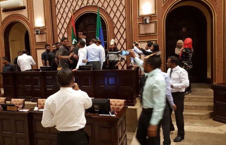 Security forces remove opposition lawmakers gathered at the parliament speaker's table while lawmaker protest.