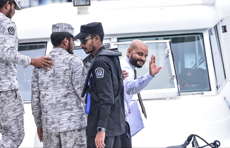 Dhiggaru MP Faris Maumoon waves as he is escorted to jail. PHOTO/MIHAARU