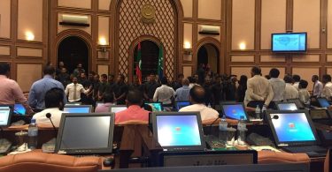 Security officers surround Speaker Maseeh inside the parliament chambers while opposition lawmakers protest.