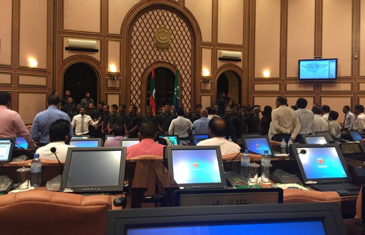 Security officers surround Speaker Maseeh inside the parliament chambers while opposition lawmakers protest.