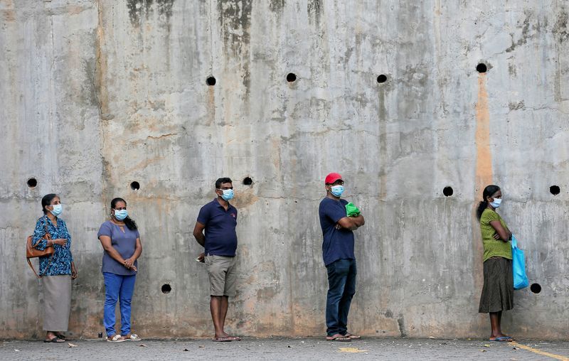 FILE PHOTO: People maintain the one-meter distance in-between each other as they stand in a line to buy groceries at a supermarket during the time government lifted the curfew in Colombo