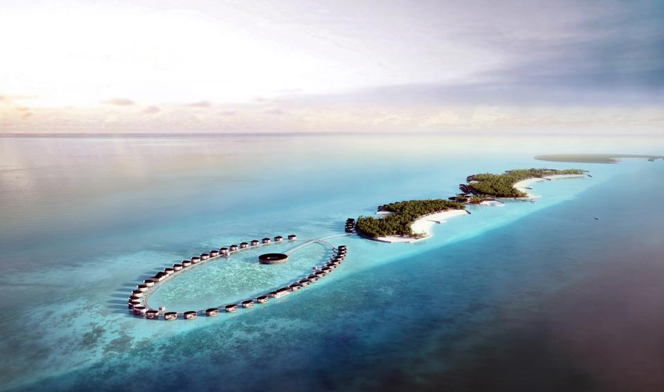 An oval string of overwater villas surrounded by turquoise water