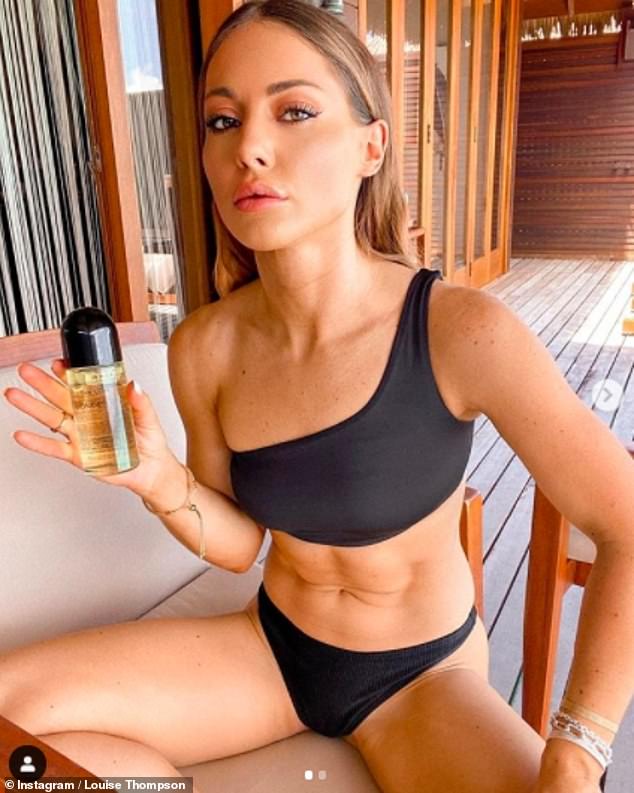 Flaunt it: She later slipped into a one-shoulder black bikini and showed off her taut stomach as she posed with a bottle of Tan Luxe oil