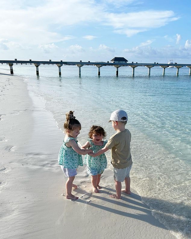 Too cute: A particularly adorable photo showed her three children holding hands as gleefully played together by the shoreline